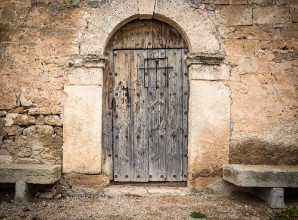 Afbeeldingen van Ancient wooden door on a stone made wall and cement benches