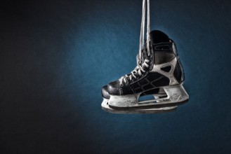 Bild på Mens hockey skates hanging on a dark background