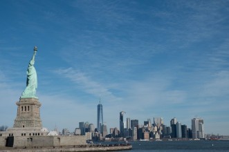 Bild på Statue of Liberty in Profile with Manhattan skyline in background Bright sunny day Wall Street and Financial District of lower Manhattan in the background  View from ferry across the harbor