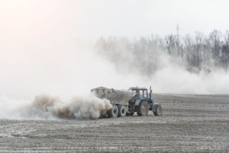 Afbeeldingen van Tractor with trailer fertilizes agricultural field in spring for sowing corn