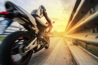 Picture of Moto da strada sfreccia vicino al guard rail al tramonto